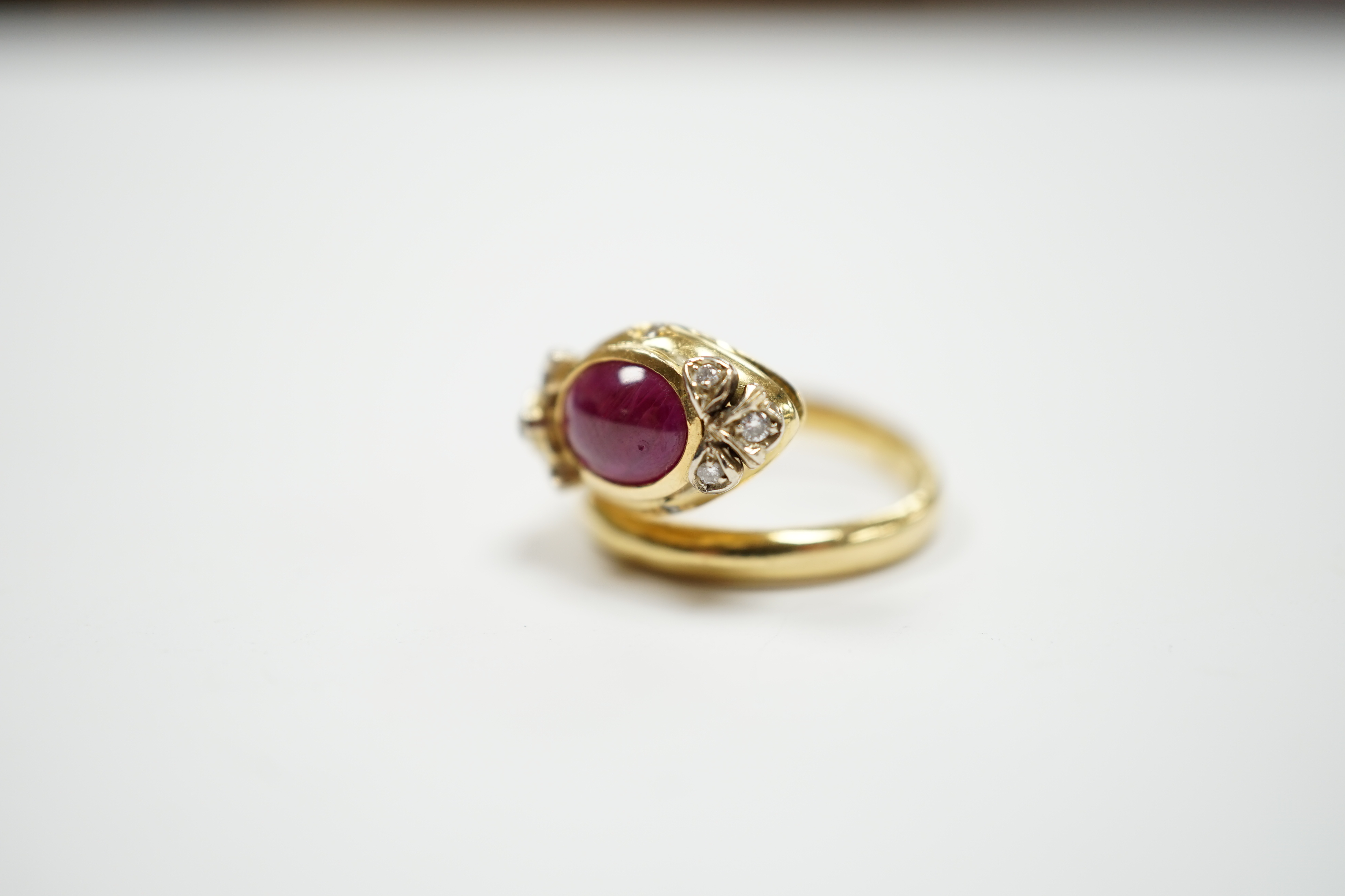 A modern Italian 750, synthetic cabochon ruby and diamond chip set coil shank dress ring, size J/K, gross weight 6.9 grams.